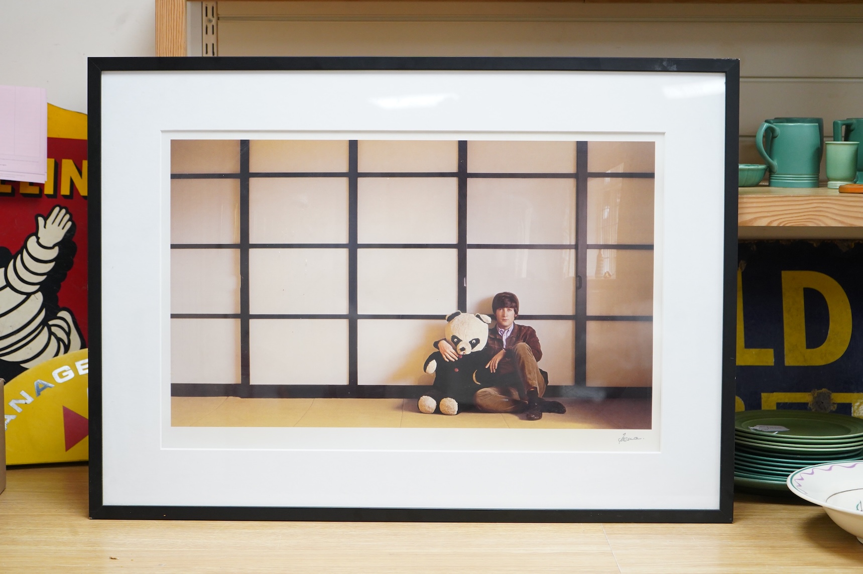 A framed and mounted photograph of John Lennon by Robert Freeman, posing with a toy panda, signed in the margin at the bottom right, 45 x 71cm